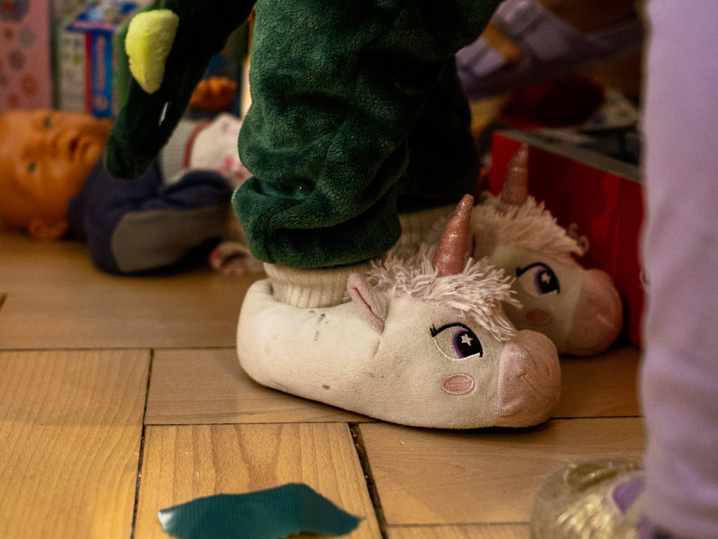 Kind in Einhorn-Hausschuhen auf dem Parkettboden